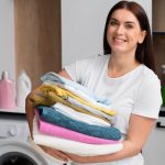 woman holding pile clean clothes